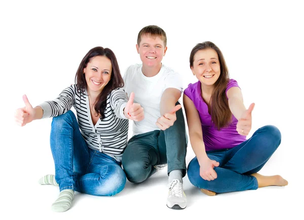 Młodzi przyjaciele, siedząc na podłodze i przedstawienie kciuki w górze Zdjęcie Stockowe