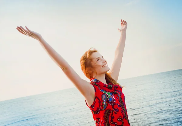 Giovane bella ragazza sulla spiaggia alzando le mani — Foto Stock