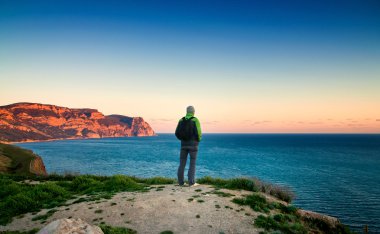 genç adam bir tepe üzerinde günbatımında duruyor.