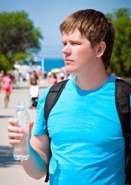 bir şişe su tutarak genç atletik erkek