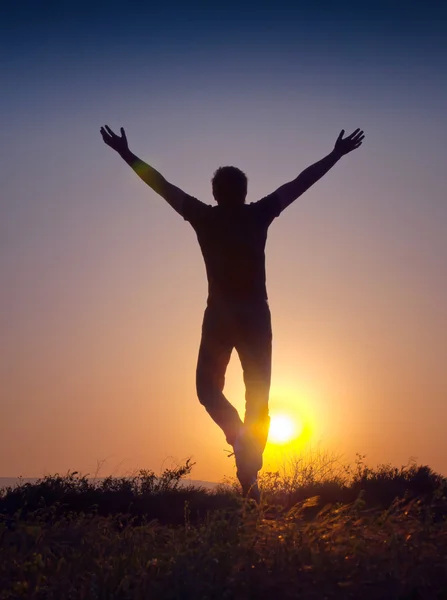 Silhouette d'un jeune homme sautant au coucher du soleil — Photo