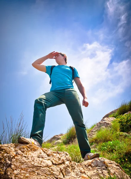 Jonge gezonde man wandelen in de bergen ziet er in de distanc — Stockfoto