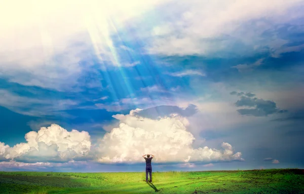 Jovem rapaz fica em um campo e o sol está brilhando sobre ele — Fotografia de Stock