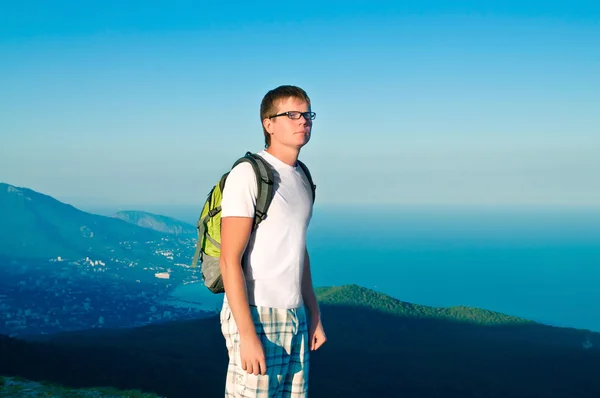 Giovane ragazzo sano con uno zaino in piedi su una collina e guardare l — Foto Stock