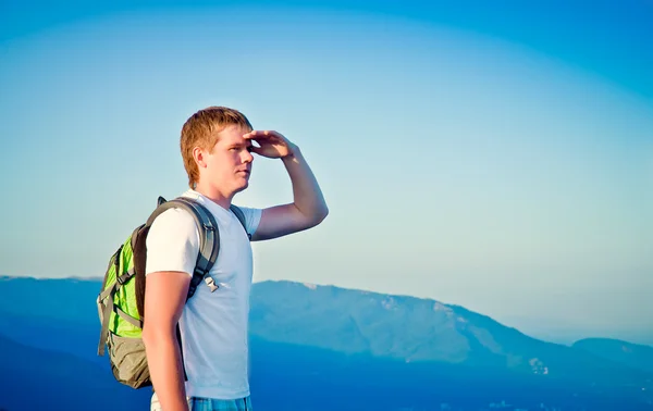 Genç adam dağlarda ve mesafe içine görünüyor — Stok fotoğraf