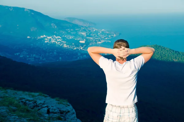 Mladý zdravý chlap stojí na kopci a sledovat krajinu — Stock fotografie