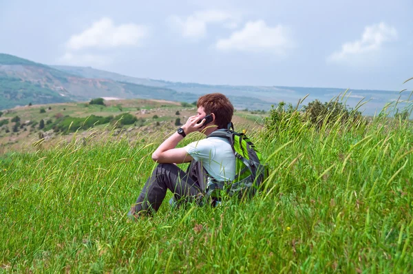 一个年轻人谈电话坐在草地上 — 图库照片