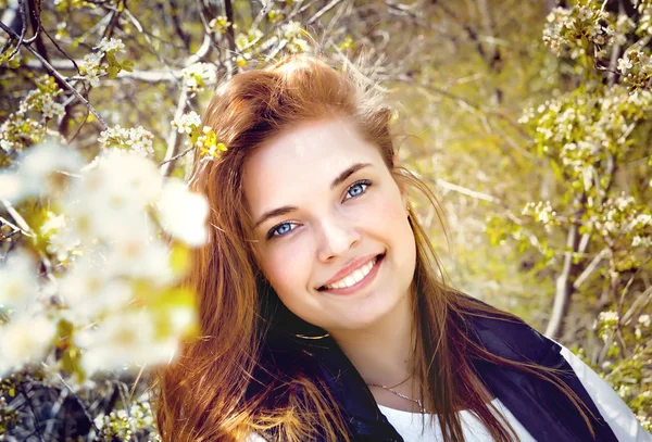 Retrato de uma jovem menina sorridente em uma árvore exuberante — Fotografia de Stock