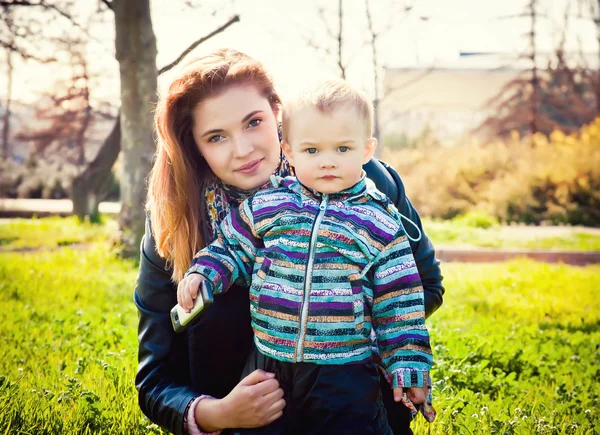 Молодая мать гуляет в парке с его маленьким сыном — стоковое фото