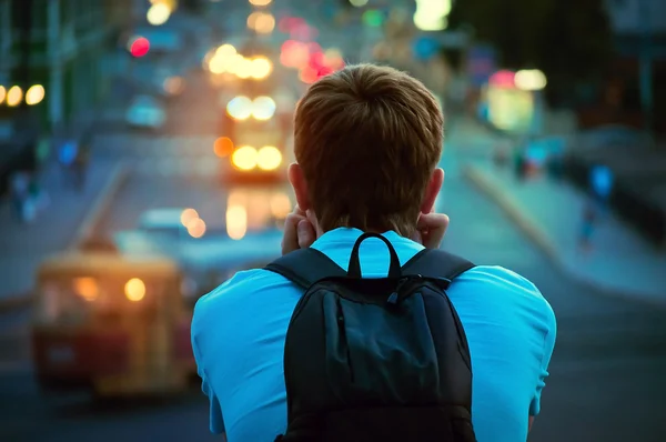 Ragazzo solitario seduto e guardando le luci della città di sera Fotografia Stock