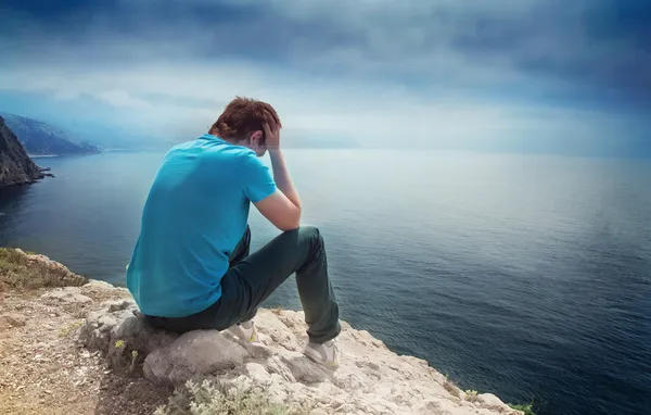 Smutný osamělý chlapec na kopci s výhledem na moře Stock Snímky
