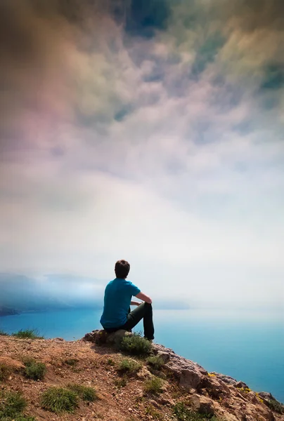 一个孤独的年轻人坐在一座小山 图库图片