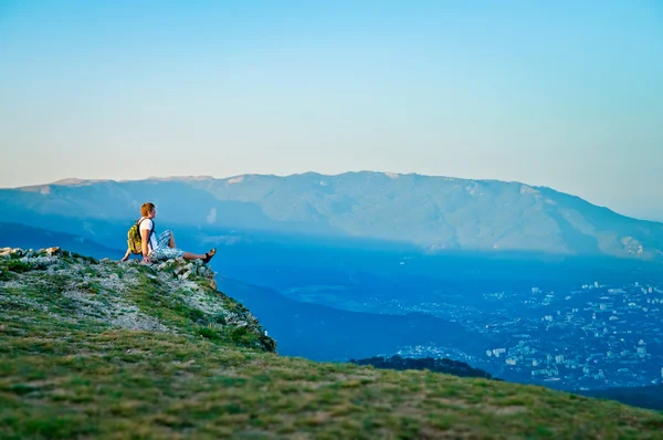 Giovane turista con zaino seduto sulla collina e godersi la sc Foto Stock