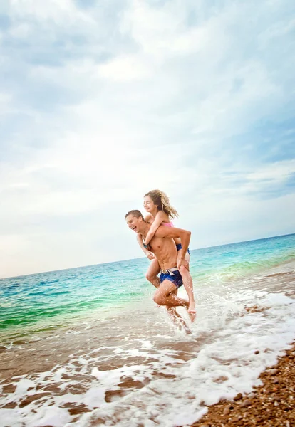 Giovane porta una ragazza sulle mani vicino al mare — Foto Stock