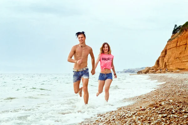 Young couple running along the beach — Zdjęcie stockowe