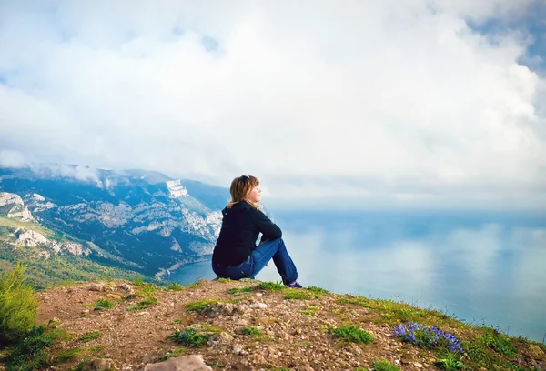 Giovane ragazza seduta su una collina con vista sul mare — Foto Stock