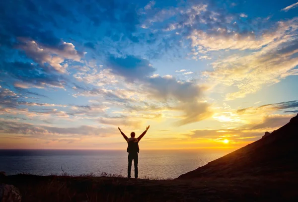 Un jeune homme se tient sur une colline surplombant la mer — Photo