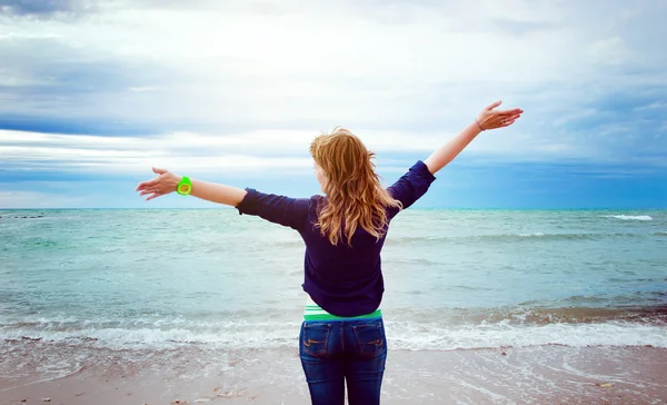 Jeune fille sur la plage avec les bras levés — Photo