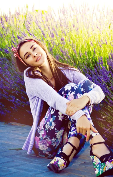 Красивая молодая девушка сидит рядом с кустами лаванды — стоковое фото