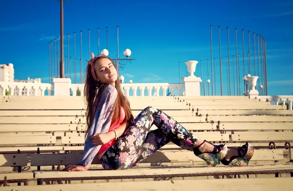 Elegante mujer joven se sienta en un banco al aire libre —  Fotos de Stock