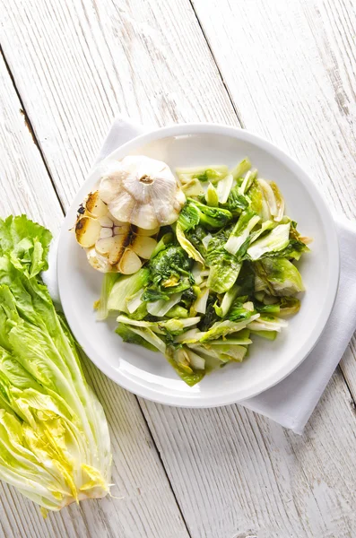 Baked Romaine lettuce with garlic and pine cores — Stock Photo, Image