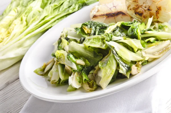 Baked Romaine lettuce with garlic and pine cores — Stock Photo, Image