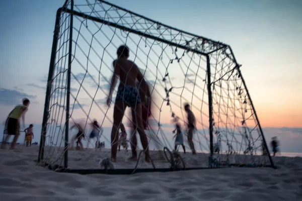 Fußball spielen am Strand bei Sonnenuntergang — Stockfoto