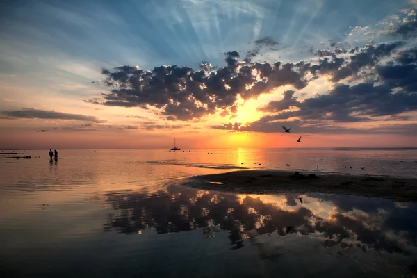 Casal caminhando na praia no mar ao pôr do sol — Fotografia de Stock