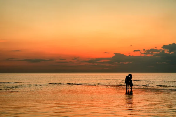 日没時にビーチでカップルが — ストック写真