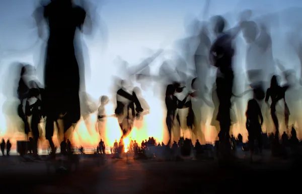 Pessoas dançando na praia contra o pôr do sol — Fotografia de Stock