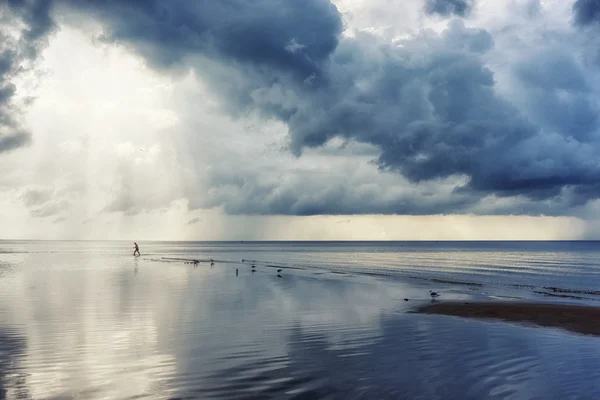 En man kommer ut i havet på bakgrund av solens strålar — Stockfoto