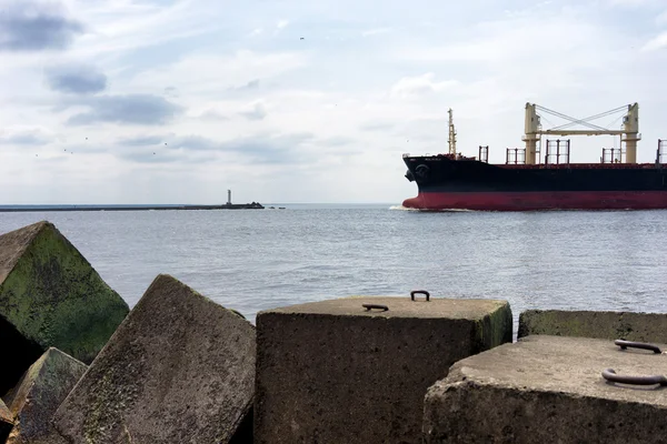 Statek towarowy wchodzi port obok latarni morskiej — Zdjęcie stockowe