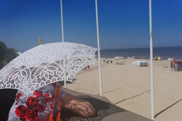 Женщина с кружевным зонтиком на пляже — стоковое фото