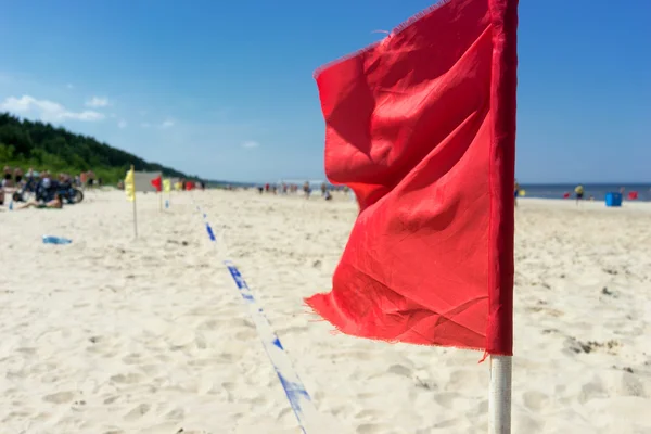 Menschen spielen Fußball am Strand vor rotem Flaggenhintergrund — Stockfoto