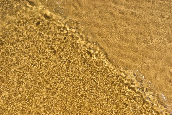Surf las olas en el mar sobre un fondo de arena de playa — Foto de Stock