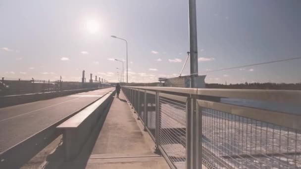 Um homem caminha sobre uma ponte sobre um rio no inverno — Vídeo de Stock