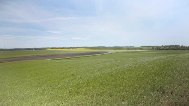 緑の芝生で丘を登ると ラトビアのフィールドの風景が見えます 車で高速道路 暖かい春の晴れた日 — ストック動画