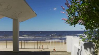 Yazın başında Jurmala sahilinde güneşli sıcak bir gün. Kumlu geniş kıyı Letonya 'da turistler için popüler bir yerdir. Sarı kumda aktif yaşam tarzı. Mavi gökyüzüne karşı leylak.