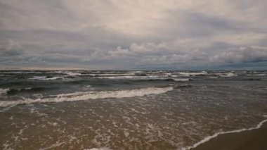 Waves on a sandy Baltic beach in a storm. Clouds over the horizon at the end of a summer day in Latvia. Long deserted beach in Vidzeme. Latvia