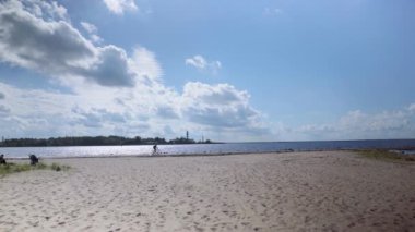 The cyclist rides along the Daugava river dam to the lighthouse at the mouth. The river flows into the Gulf of Riga of the Baltic Sea. A popular vacation spot for residents of Riga