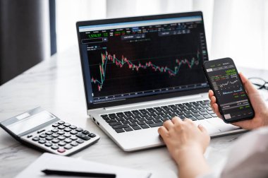 Borsa verileri ile el ele tutuşan akıllı telefon ve çevrimiçi hisse senedi ticareti yapmadan önce analiz etmek ve kontrol etmek için dizüstü bilgisayar grafiği ve grafiği kullanın
