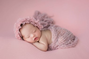 Mutlu şirin Asyalı bebek pembe arka planda uyuyor.