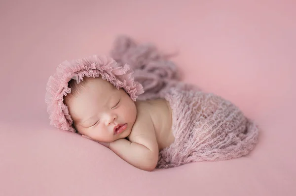 Mutlu şirin Asyalı bebek pembe arka planda uyuyor.