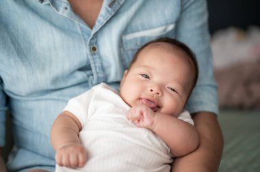 Baba kucağında oturan tatlı, tatlı bir kız bebek.