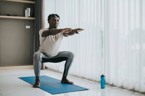 African American Man Doing Squat Exercise Workout Livingroom Yoga Mat Image En Vente