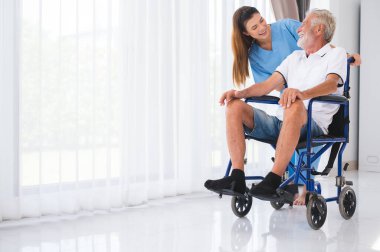 Happy Asian nurse or caregiver caring for senior old elderly disable caucasian man in wheelchair