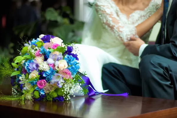 Свадебный букет рядом с женихом и невестой — стоковое фото