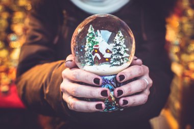 kar küresi üzerinde Noel Fuarı tutan kadın