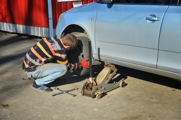 Мужчина меняет шины на машине на заправке — стоковое фото
