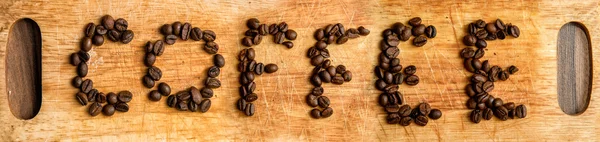 Inscriprion of coffee grains on wooden background — Stock Photo, Image